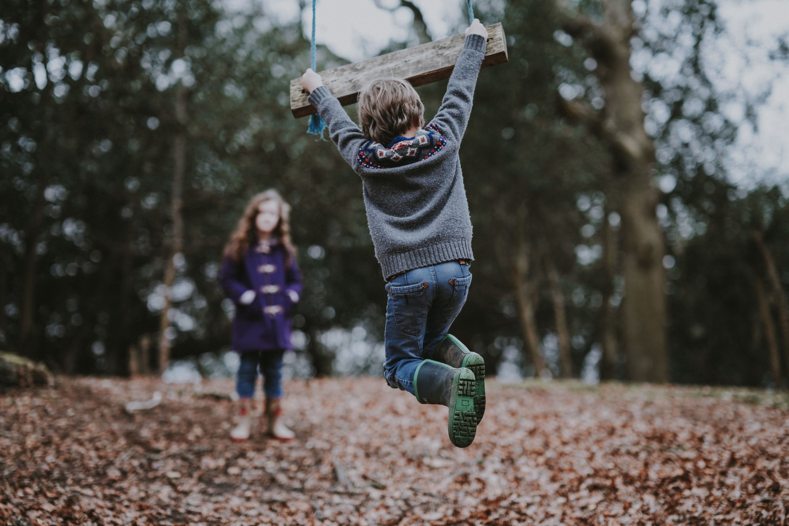 Two children playing in the woods.